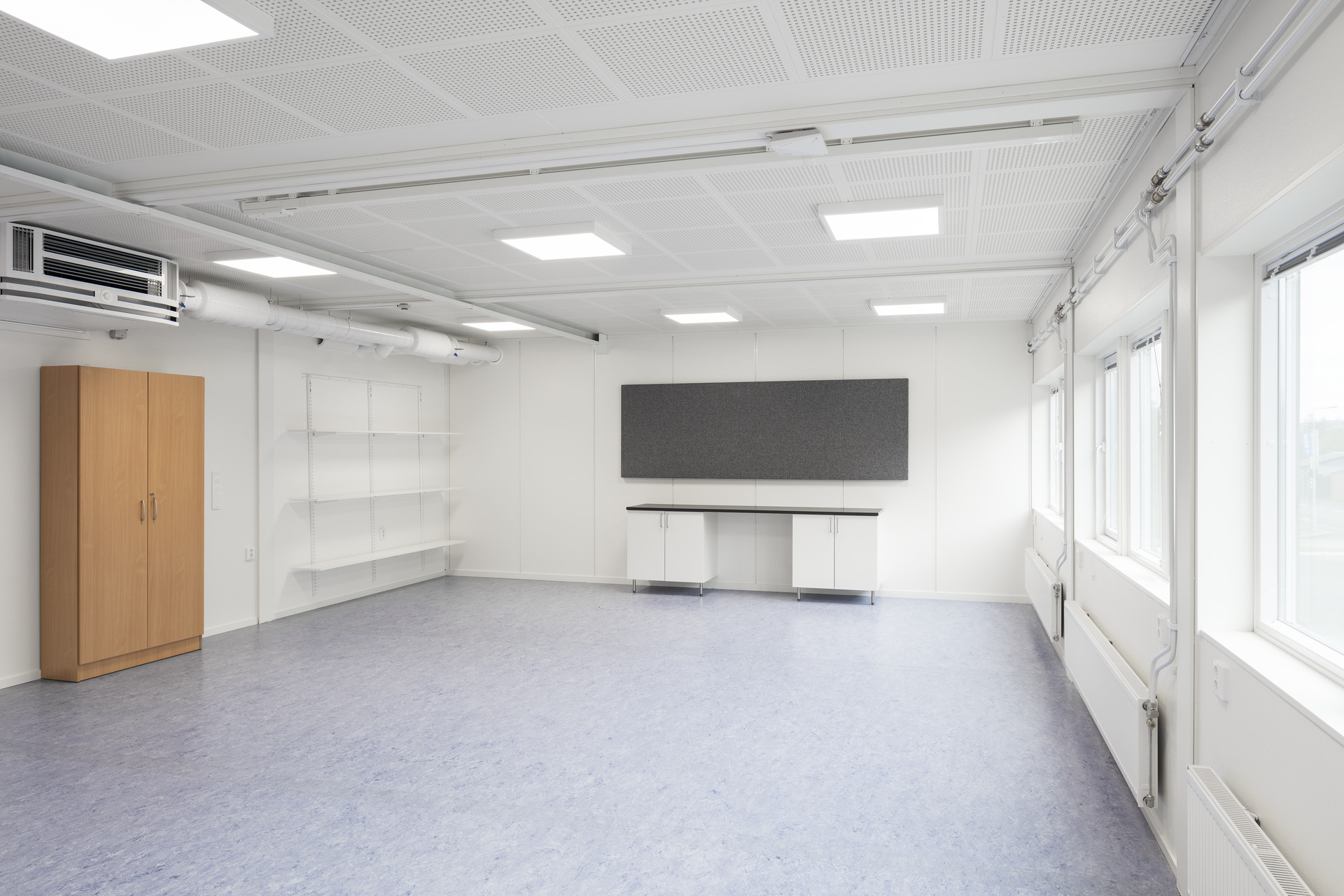 Ljust och flexibelt invändigt rum i skolmodullösning från Expandia, med stora fönster, god belysning, förvaringsskåp, arbetsbänk och ytor anpassade för undervisning eller grupparbete.