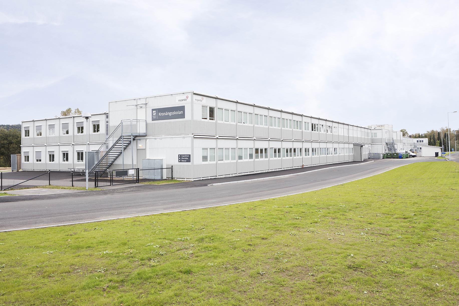 Evakueringsskola vid Kronängsskolan i Borås med två våningar klassrum i en modullösning från Expandia, placerad längs en asfalterad väg med grönområden runtom.
