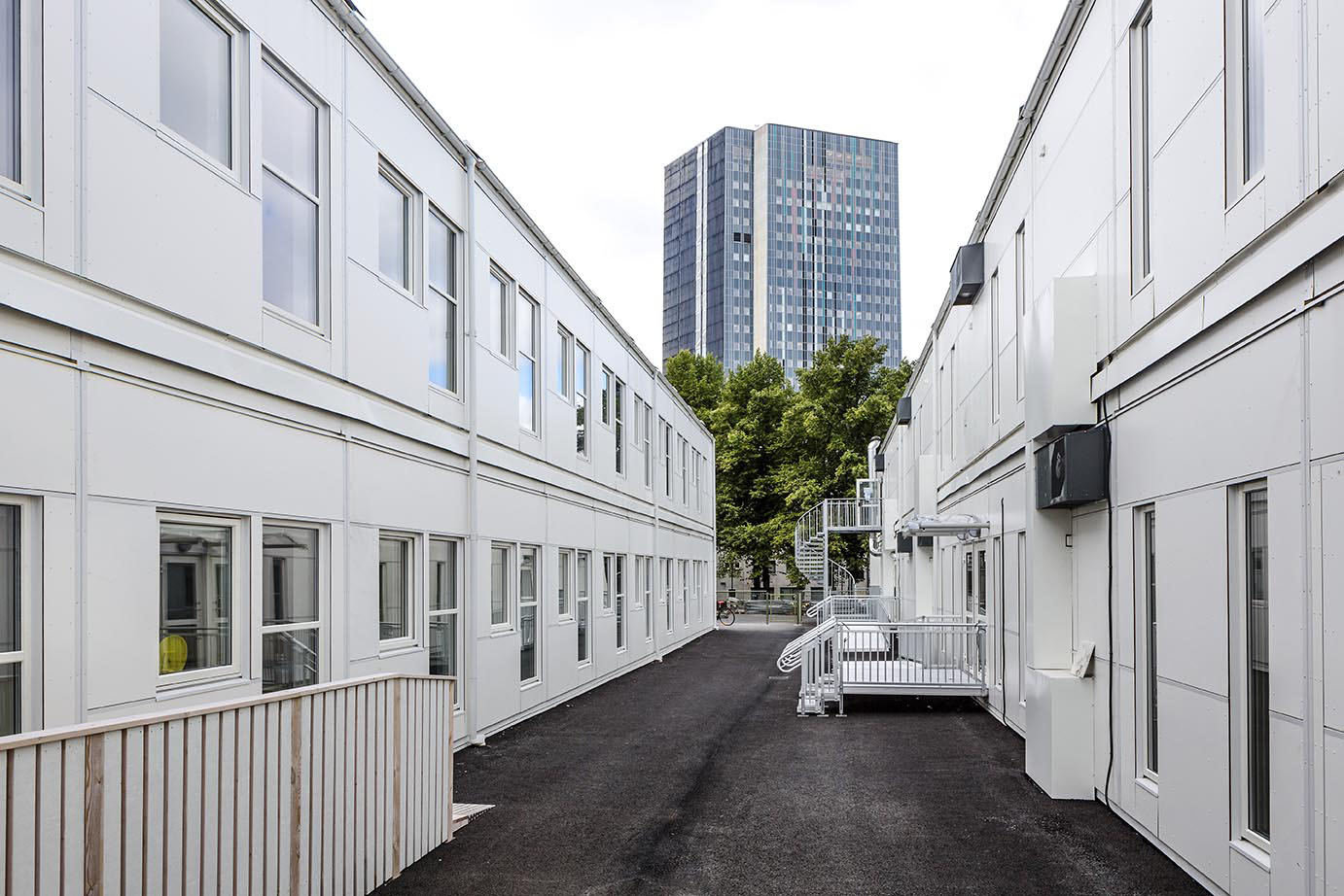 Skolmoduler från Expandia vid Sveaplansskolan i Stockholm. Två parallella tvåplansmoduler med gångyta emellan, fönsterrader längs fasaderna och ramper samt trappor som förbinder våningsplanen, placerade i en tillfällig skolmiljö.