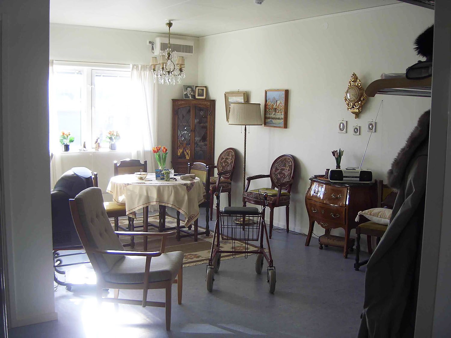 Möblerat vardagsrum i boendemoduler från Expandia med matbord, stolar, fåtöljer och traditionell inredning som skapar en hemlik och trygg miljö.