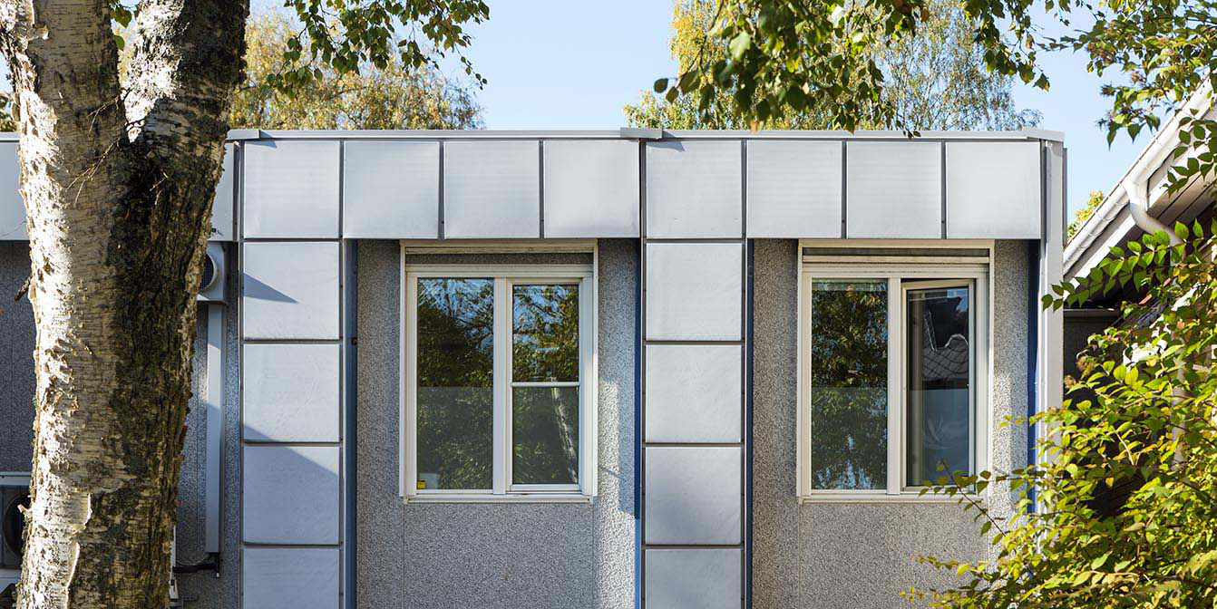 Exteriör av moduluppförd verksamhetslokal från Expandia med fönster och fasadpartier, omgiven av träd och grönska.