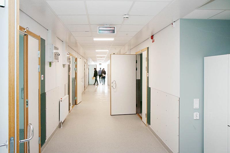 Korridor i modul från Expandia vid Östra sjukhuset i Göteborg, med vårdrum längs sidorna och personer längre ner i gången.