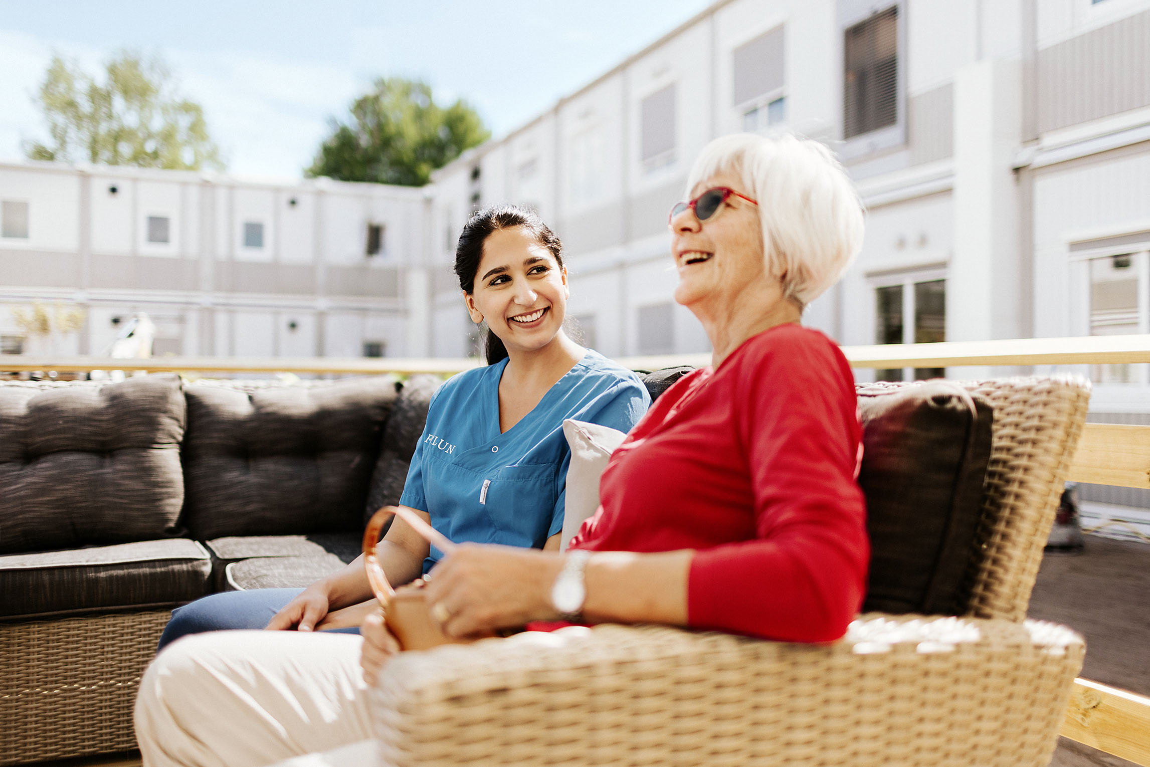 Vårdpersonal och äldre kvinna skrattar utanför vårdmoduler
