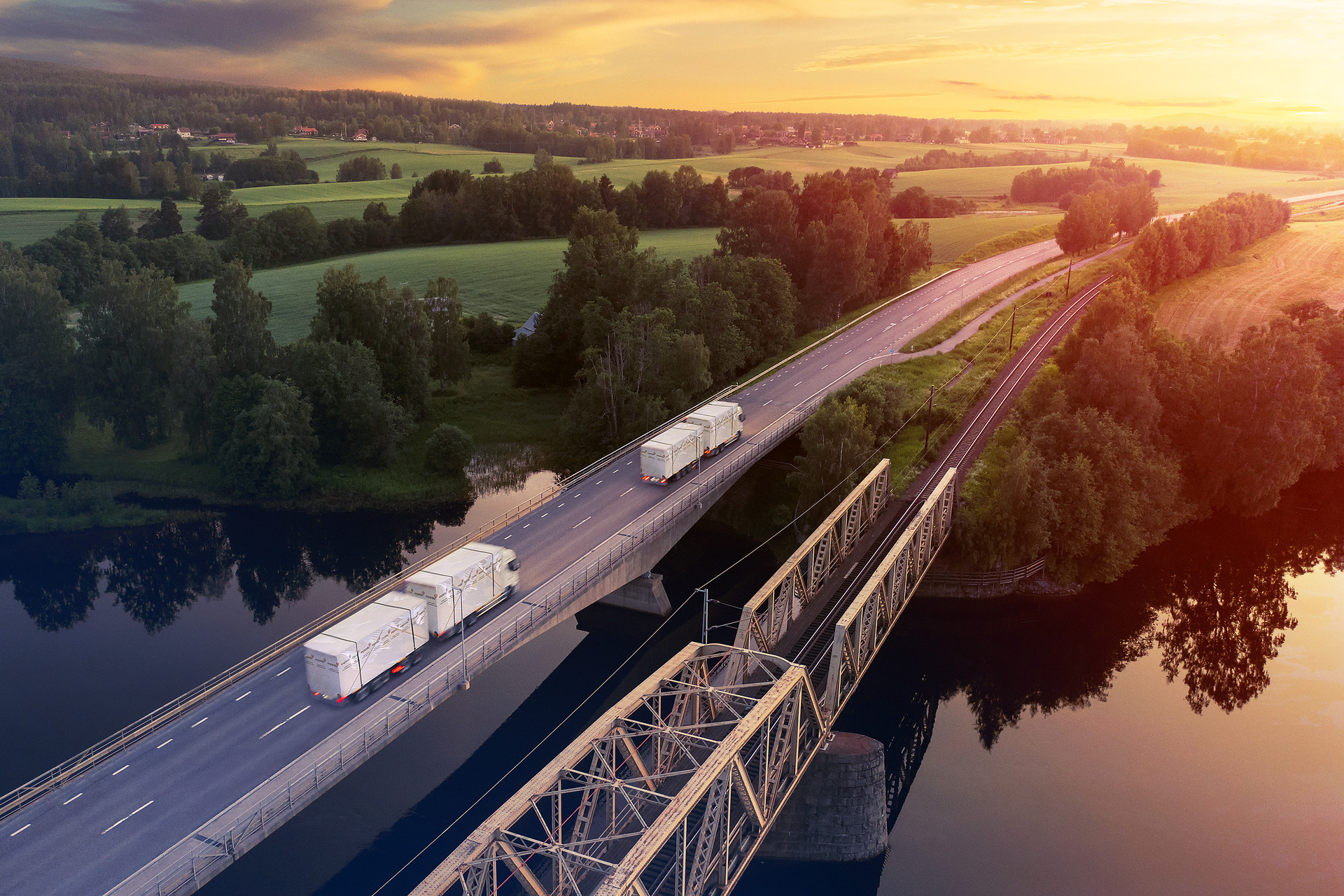 lastbilar kör i soluppgång bredvid järnväg